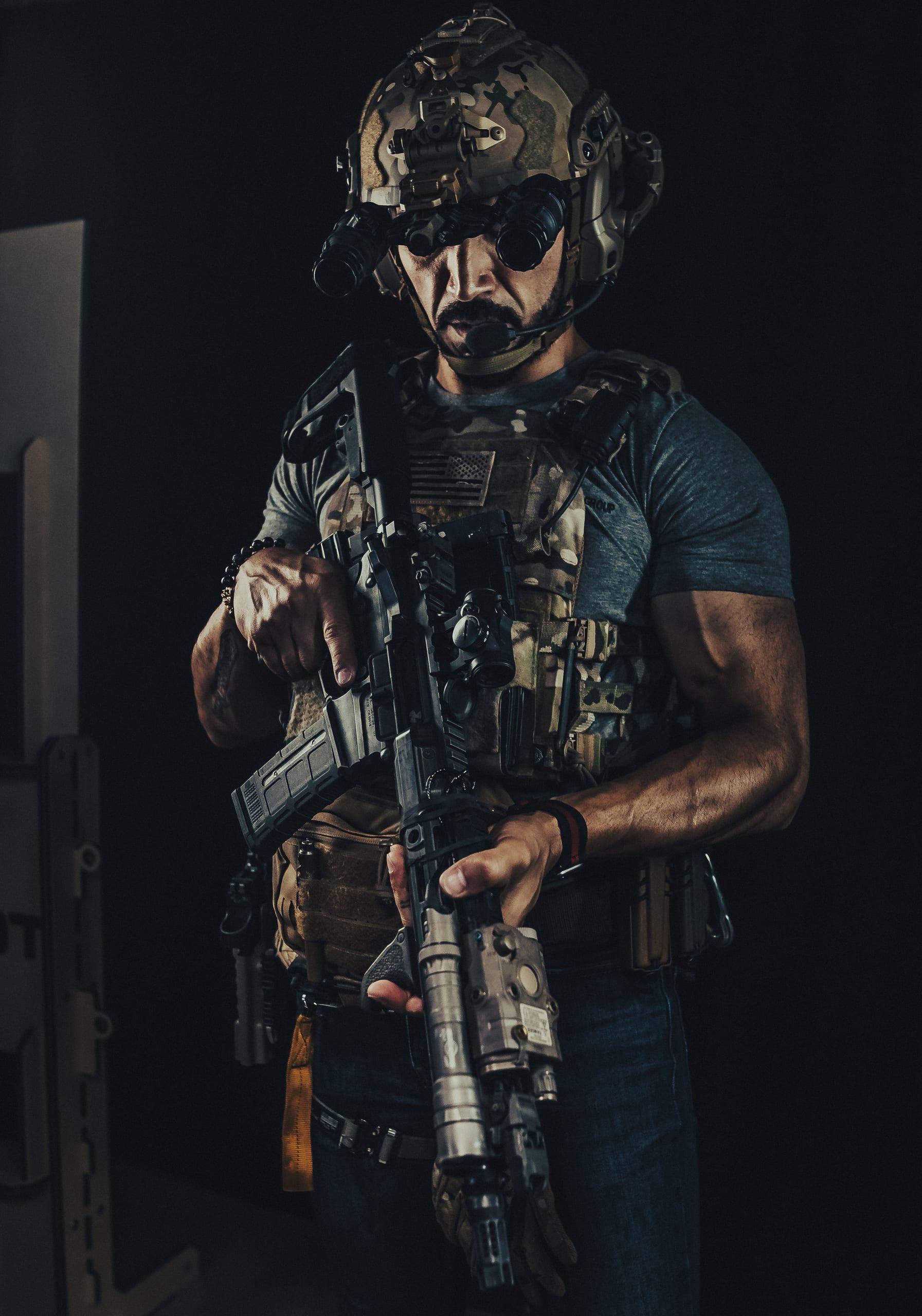 An operator in helmet and night vision holding a suppressed rifle